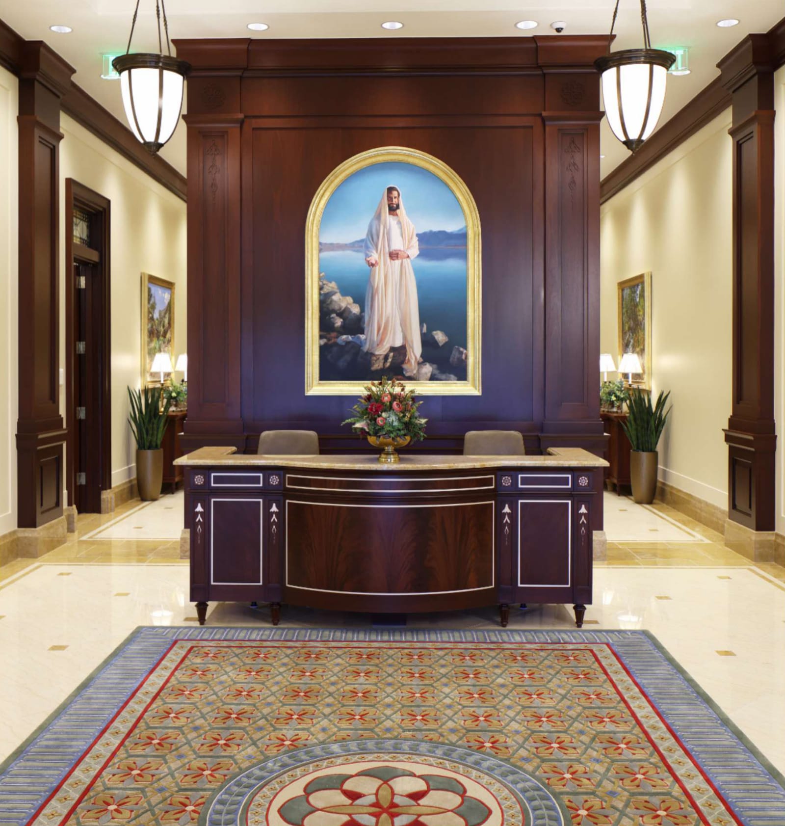 Recommend desk in the temple entrance foyer: a dark wood desk beneath an arched painting of Jesus Christ, flanked by hanging lanterns